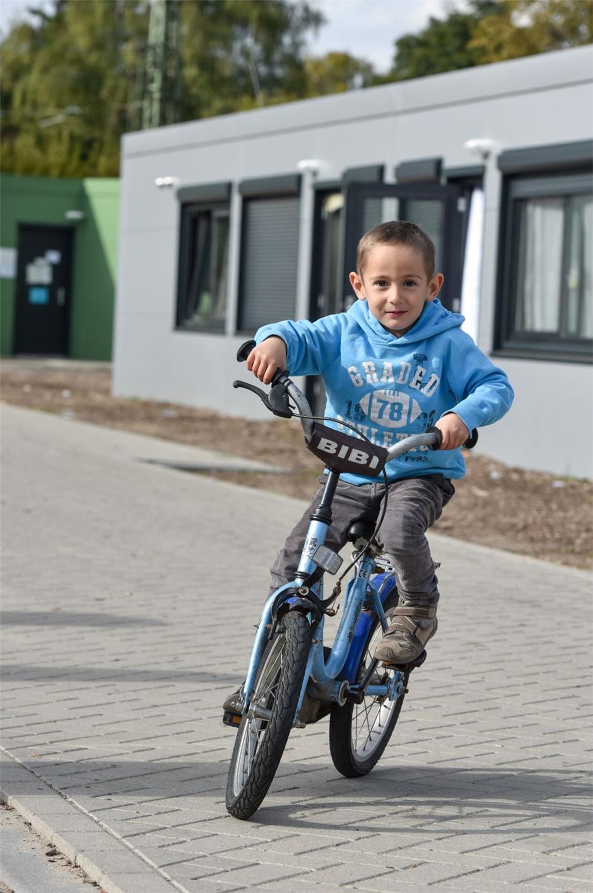 Ein Junge auf einem Fahrrad auf dem Hof eines Flüchtlingswohnheims